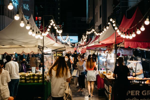 Foto van Markus Winkler Bustling night market scene with shoppers exploring colorful stalls and string lights.