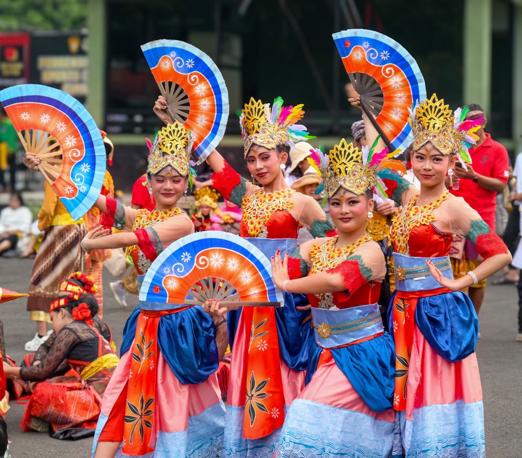 Elderly musicians playing traditional gamelan instruments indoors with regional attire.