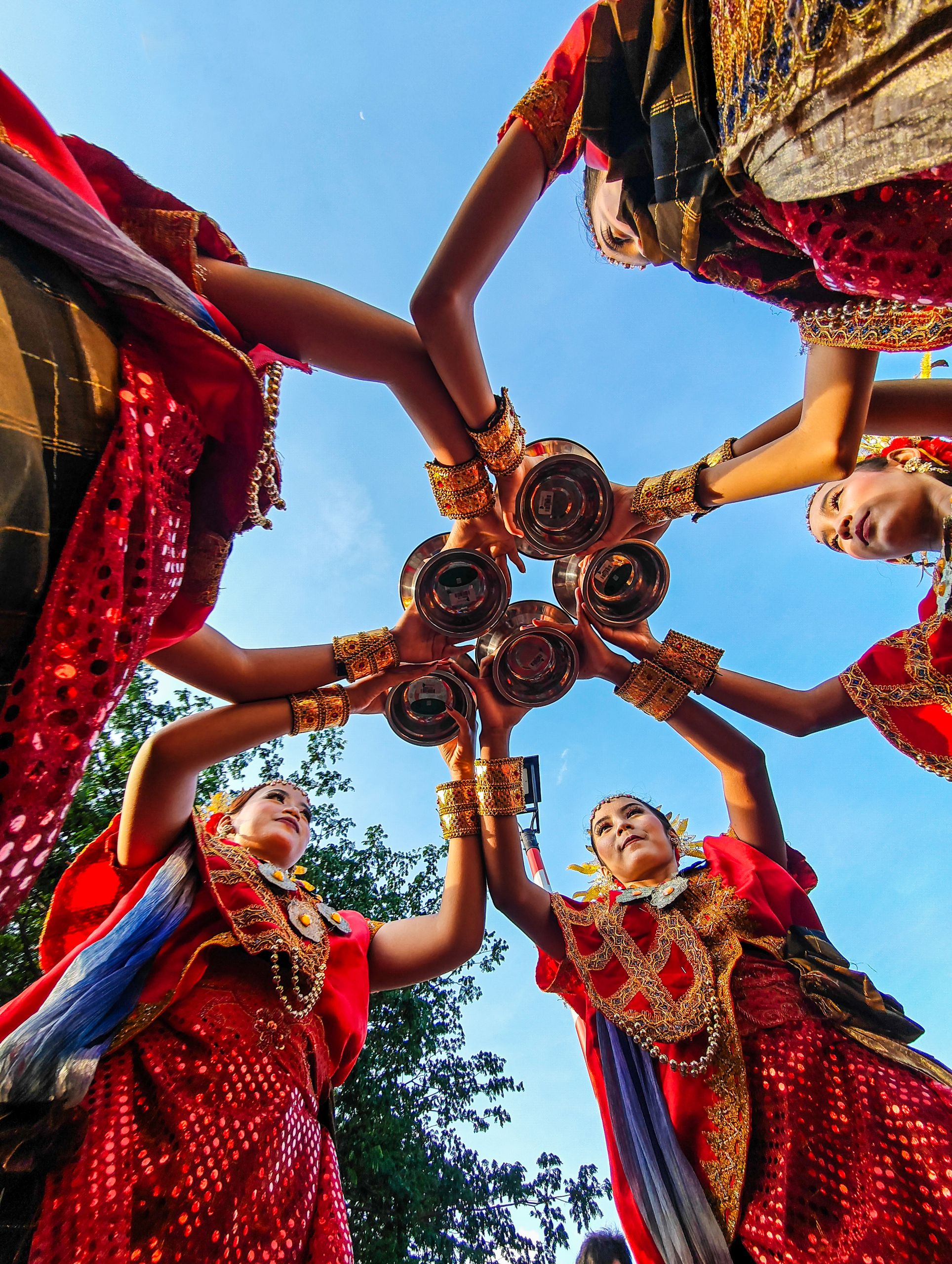 Vibrant traditional dance with women in cultural attire, forming a circle under a blue sky in Jakarta.